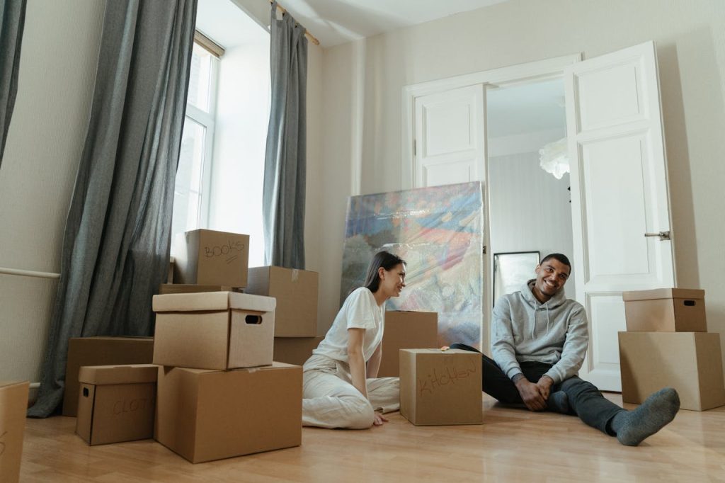 A happy couple surrounded by boxes while moving into a new apartment, symbolizing fresh beginnings.