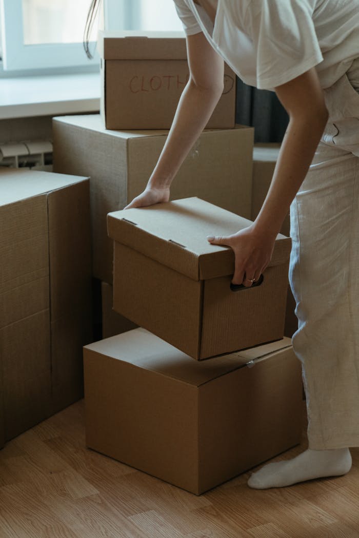 A woman packing cardboard boxes in her new apartment, symbolizing moving and relocation.